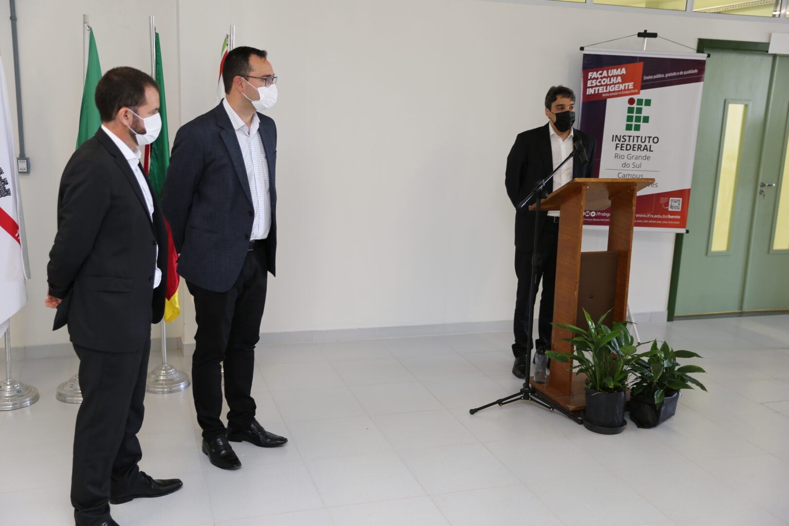 Diretor geral do Campus Bento Gonçalves discursando em púlpito. Ao lado, reitor do IFRS e prefeito de bento Gonçalves.