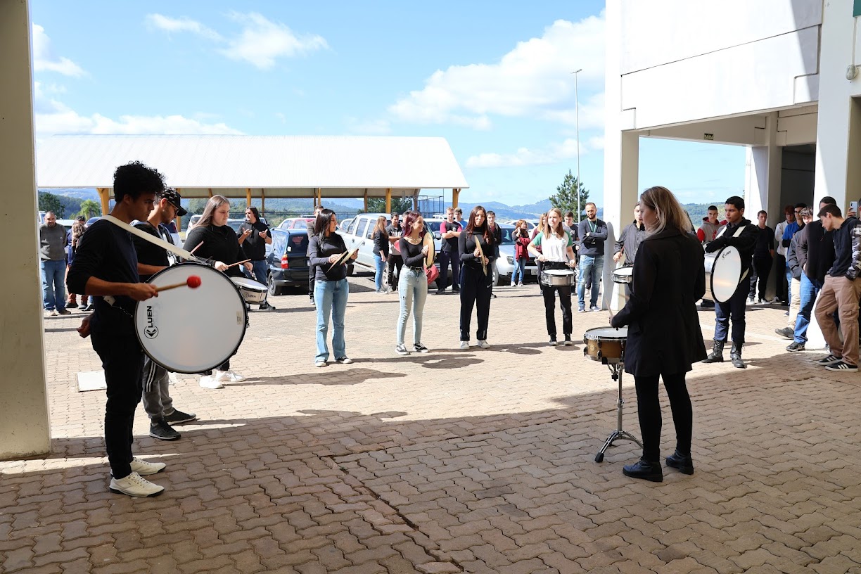 Apresentação musical de alunos que toram tambor e outros instrumentos musicais.