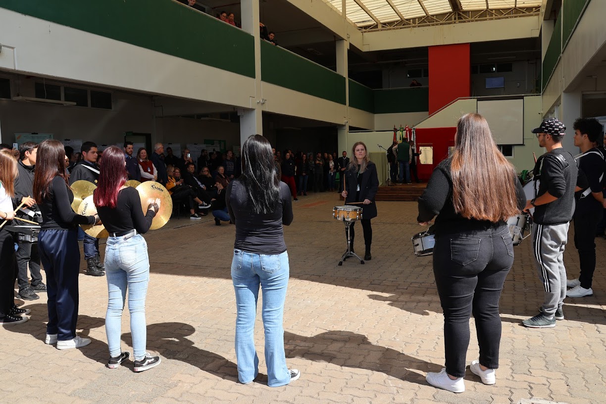 Apresentação musical de alunos que toram tambor e outros instrumentos musicais.